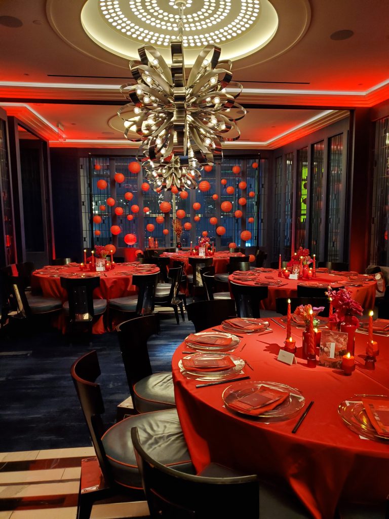 Elegant red table clothes draped over circular tables with red accompaniments